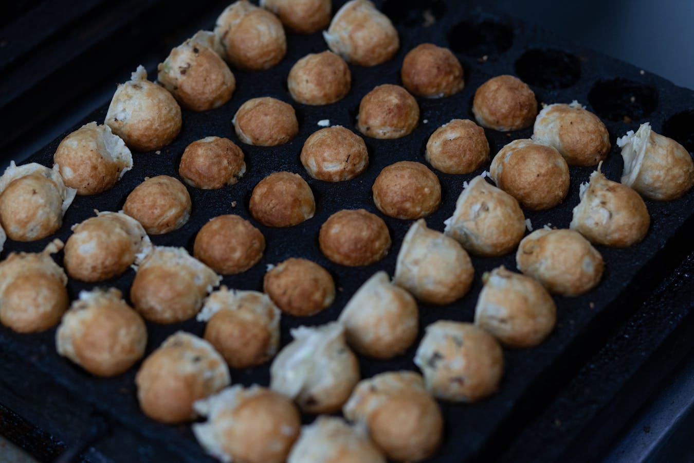 Fresh takoyaki cooking on a grill in Osaka - must try food for first-time visitors