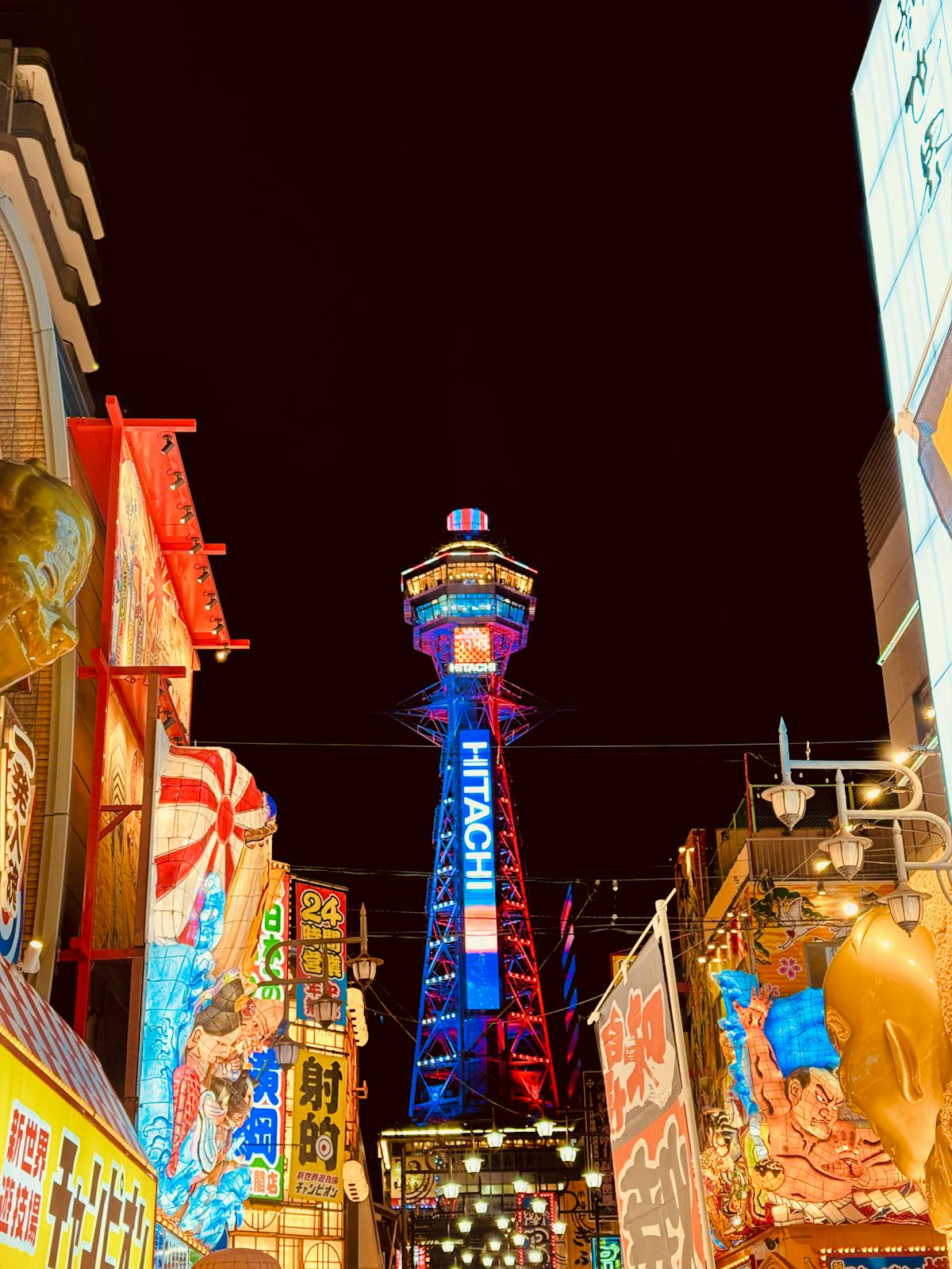 Tsutenkaku Tower surrounded by neon signs in Shinsekai Osaka neighborhood at night