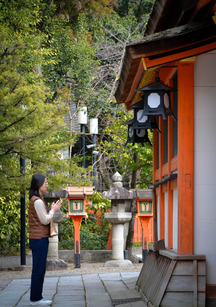 Woman praying at Shinto shrine in Japan - spiritual experience at Osaka temples and shrines