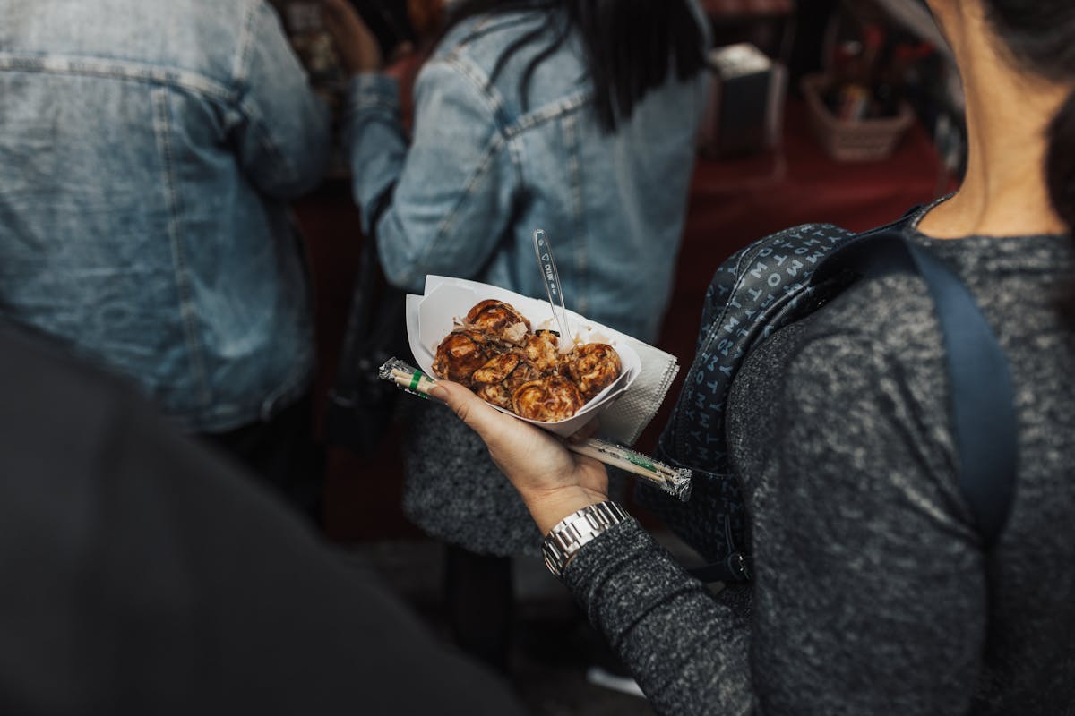 Osaka with kids enjoying takoyaki street food at a market stall