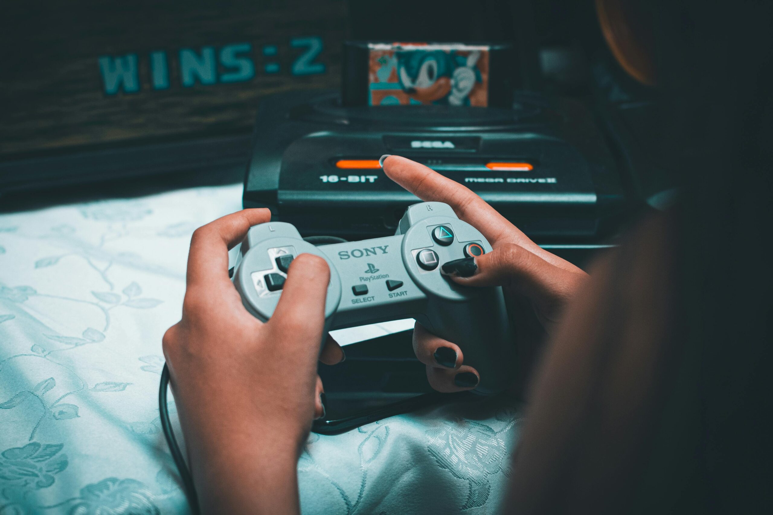 Hands holding a vintage controller next to a classic console, the kind sold in Den Den Town
