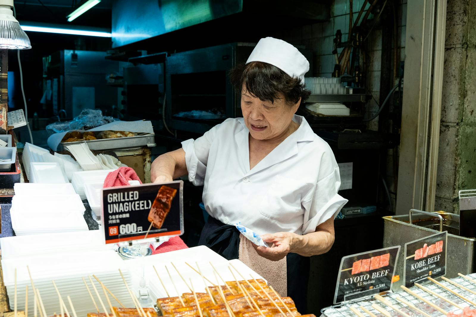 Chef grilling unagi skewers at a Nishiki Market food stall in Kyoto