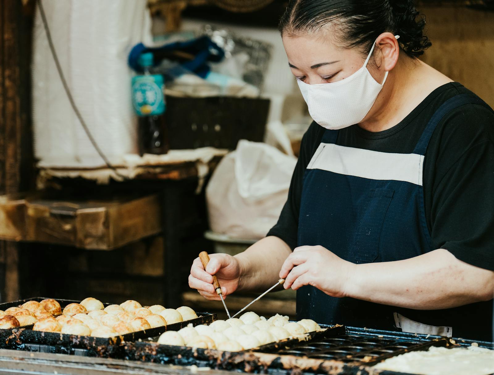 A street vendor cooking takoyaki at a stall in Dotonbori, Osaka