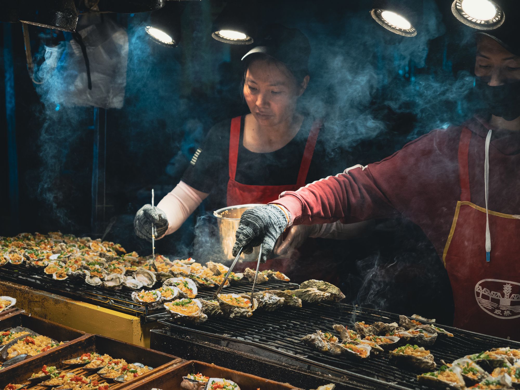 Oysters grilling at a market counter, a Kuromon Market staple in Osaka