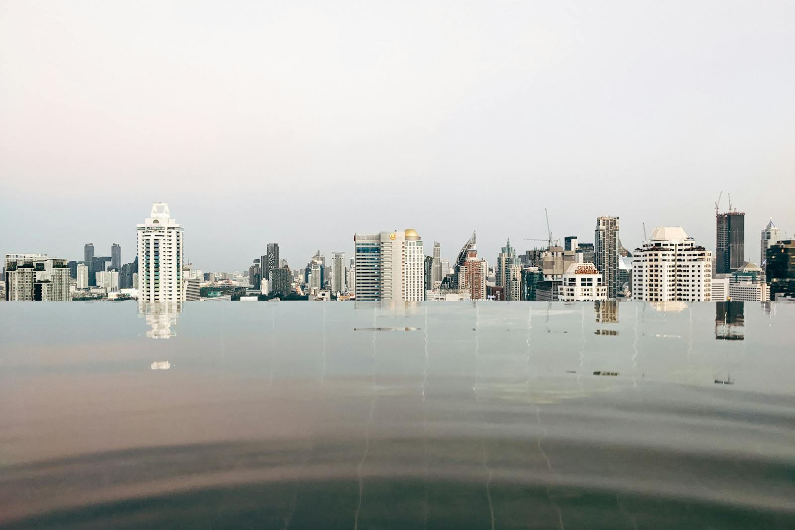 Rooftop infinity bath over a city skyline at night, like Osaka onsen hotel sky spas