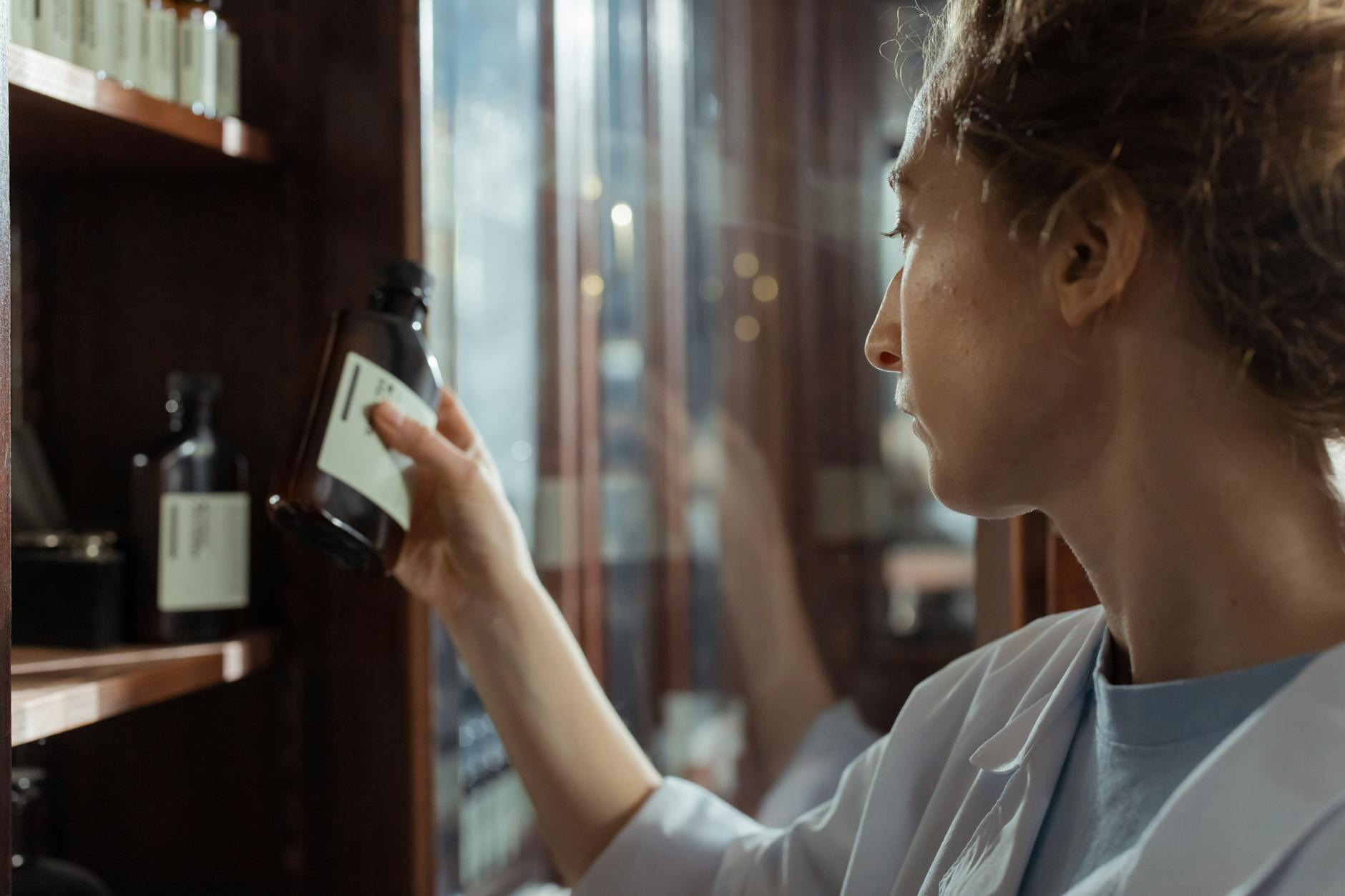 A pharmacist selecting medication from a shelf, where travellers handle minor illness in Osaka