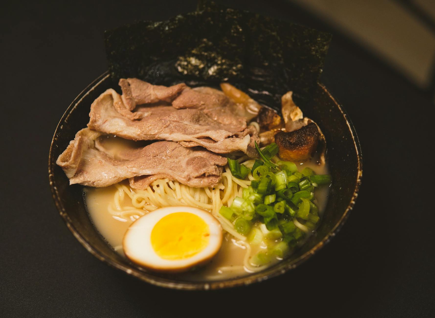 A rich bowl of tonkotsu ramen topped with egg, nori and green onion, the best ramen Osaka style