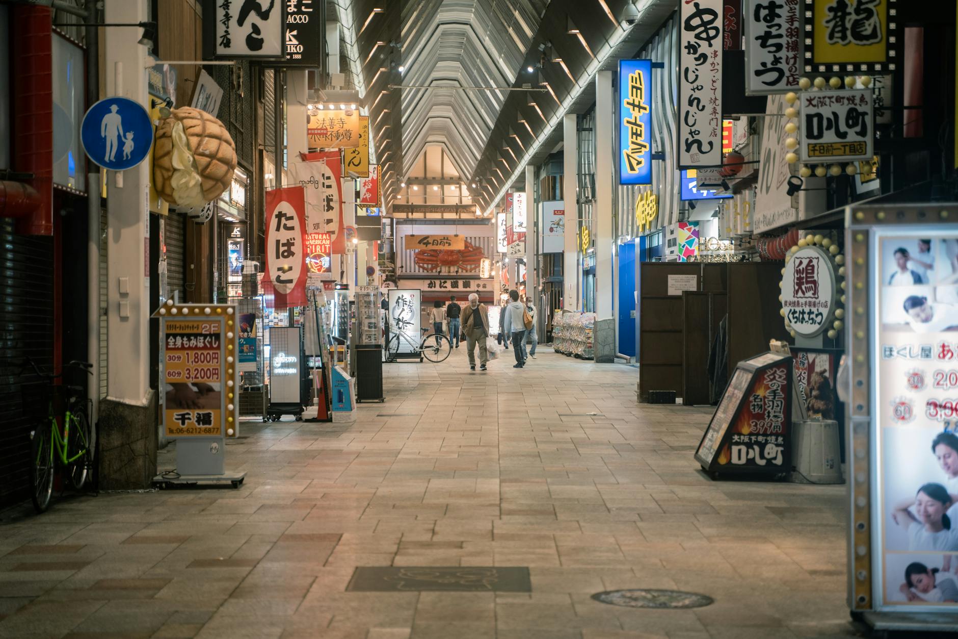 Shoppers walking past colourful storefronts in the Shinsaibashi arcade, Osaka