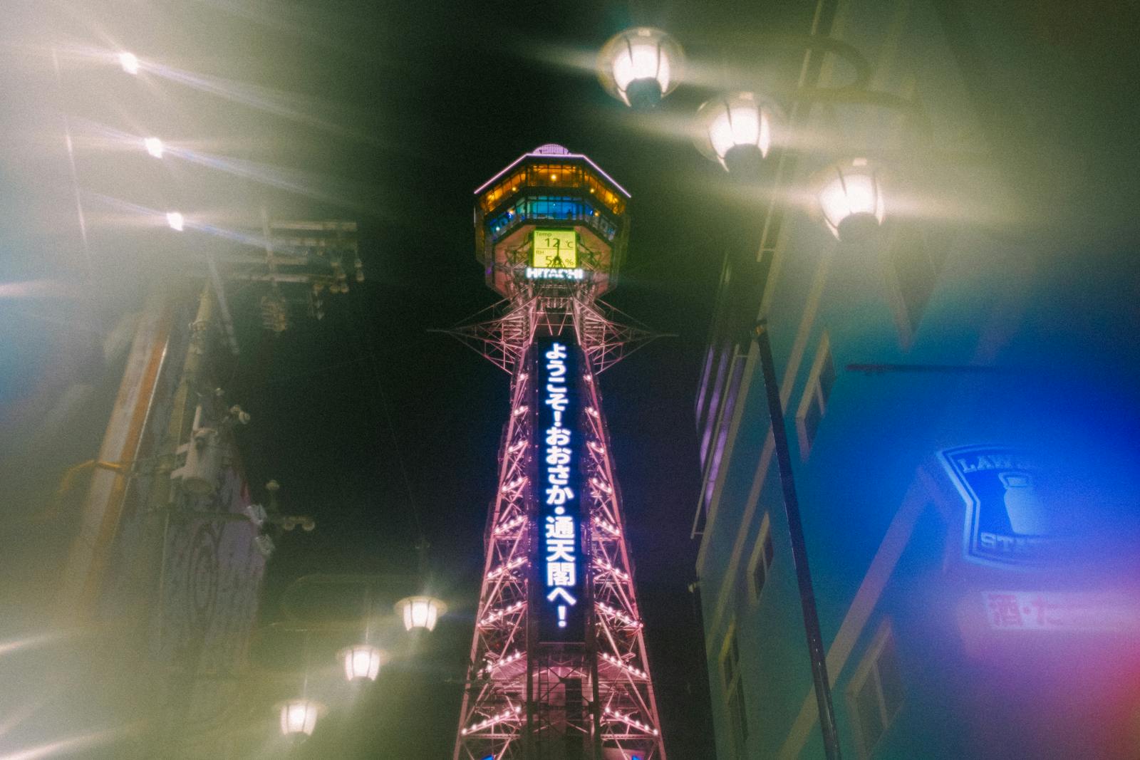 Shinsekai Osaka guide: Tsutenkaku Tower lit up at night above the retro district