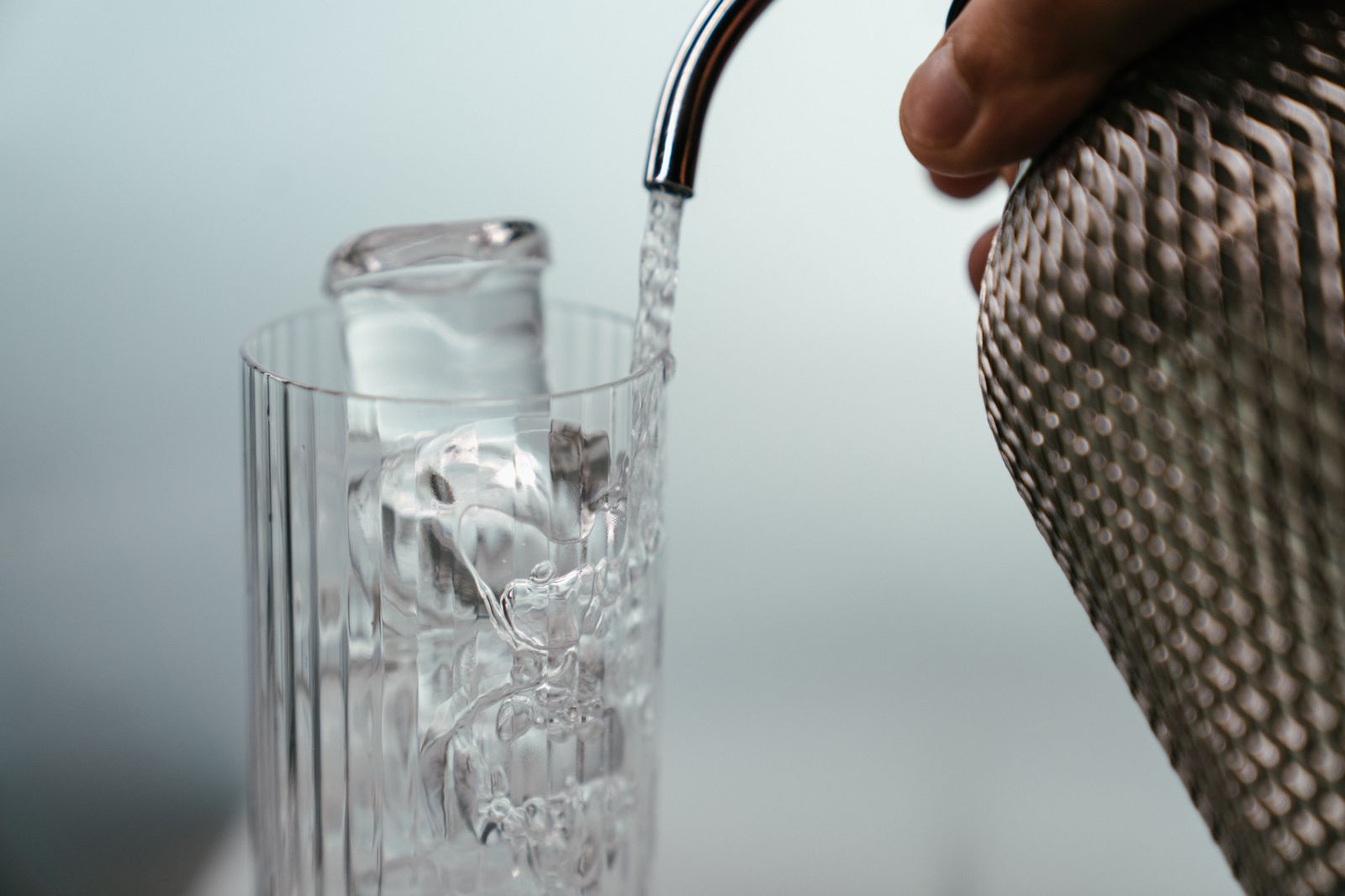 Soda water being poured over a long ice spear in a tall highball glass