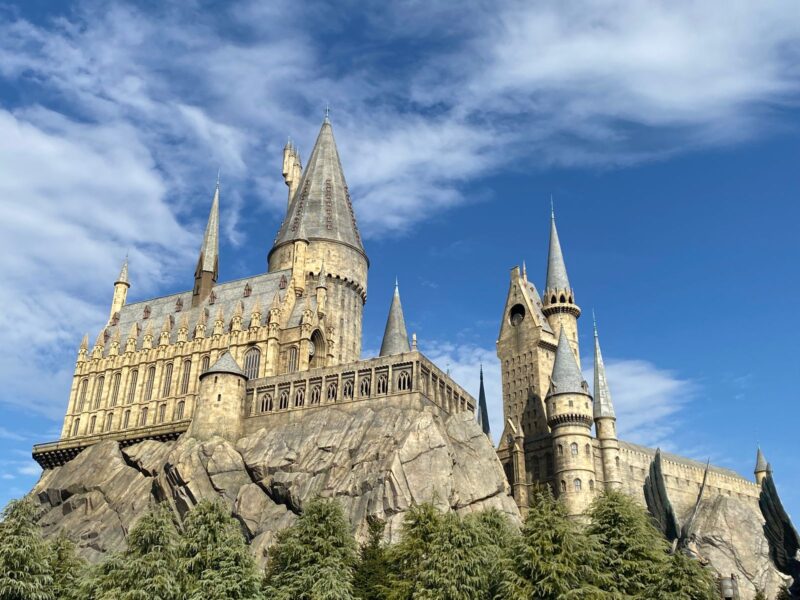 Hogwarts Castle rising above pine trees against a blue sky