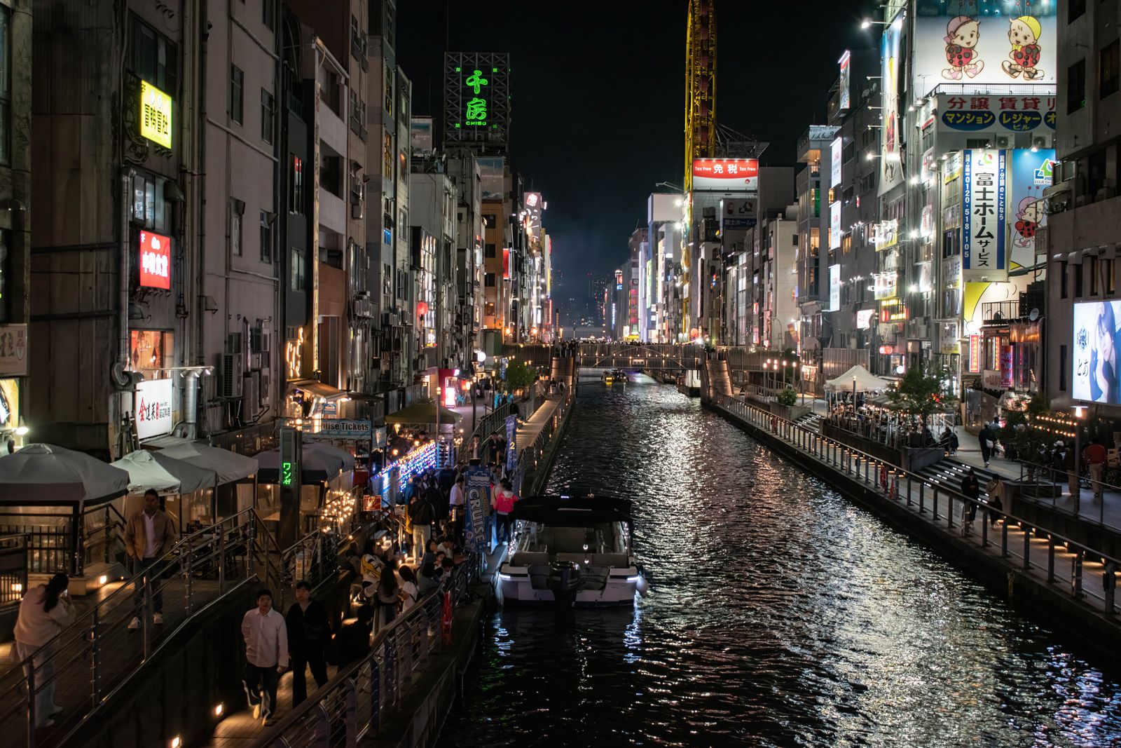 Osaka itinerary planning - Dotonbori canal at night with neon signs and a sightseeing cruise boat