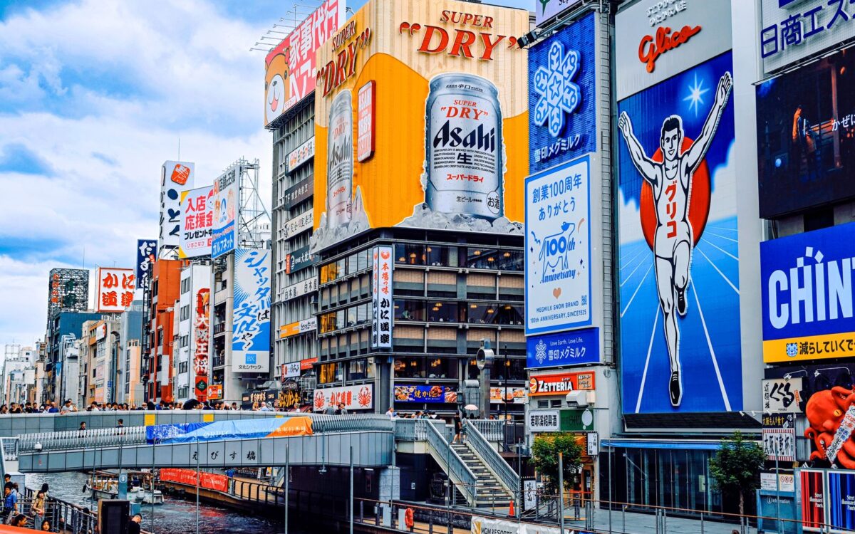 The Glico running man and Asahi signs above Ebisu Bridge on Dotonbori, Osaka, on a bright afternoon