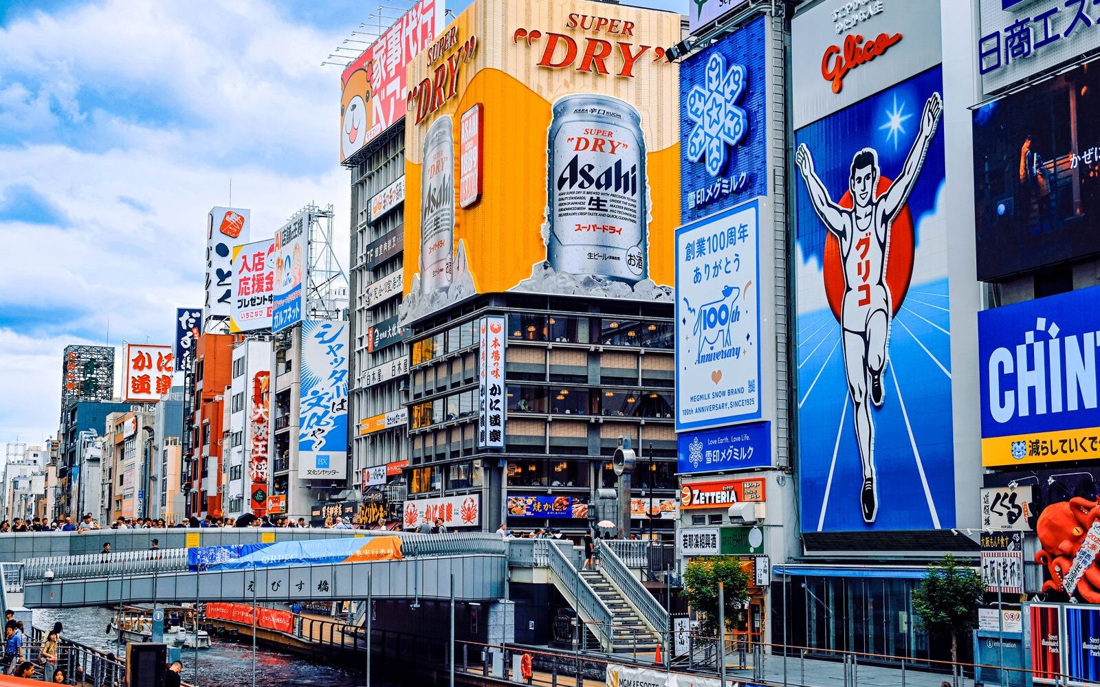 The Glico running man and Asahi signs above Ebisu Bridge on Dotonbori, Osaka, on a bright afternoon