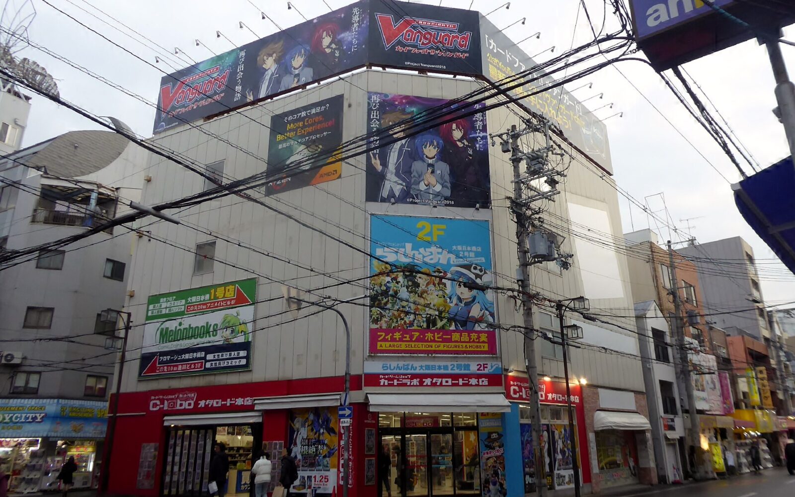 Anime billboards cover a corner building above card and figure shops on Otaku Road in Osaka’s Den Den Town.