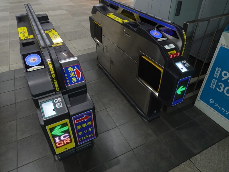 Automatic ticket gates at Osaka Metro Umeda Station have blue IC touch pads, QR readers and illuminated green arrows.