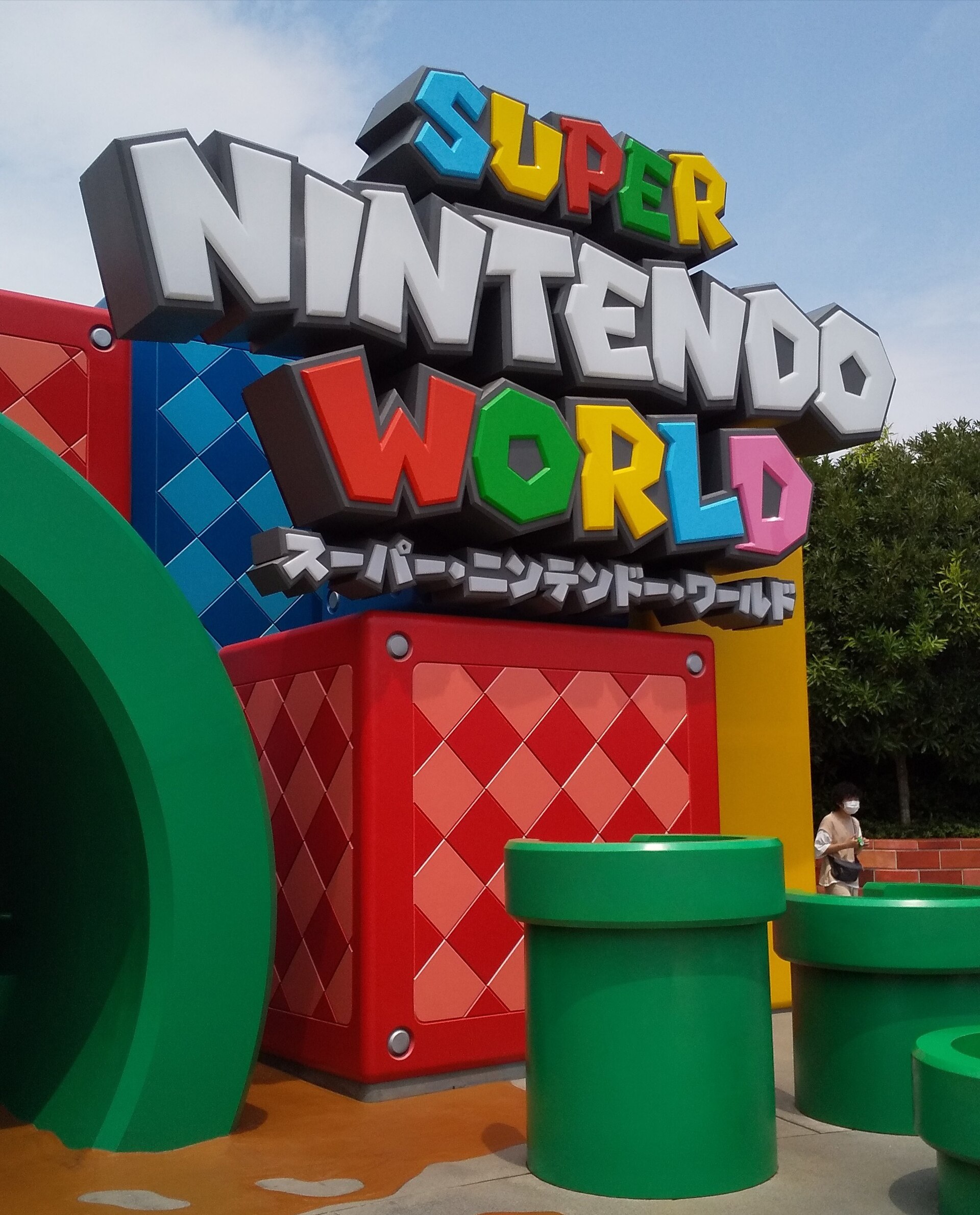 Colorful Super Nintendo World lettering towers over green pipes beside the entrance at Universal Studios Japan in Osaka.