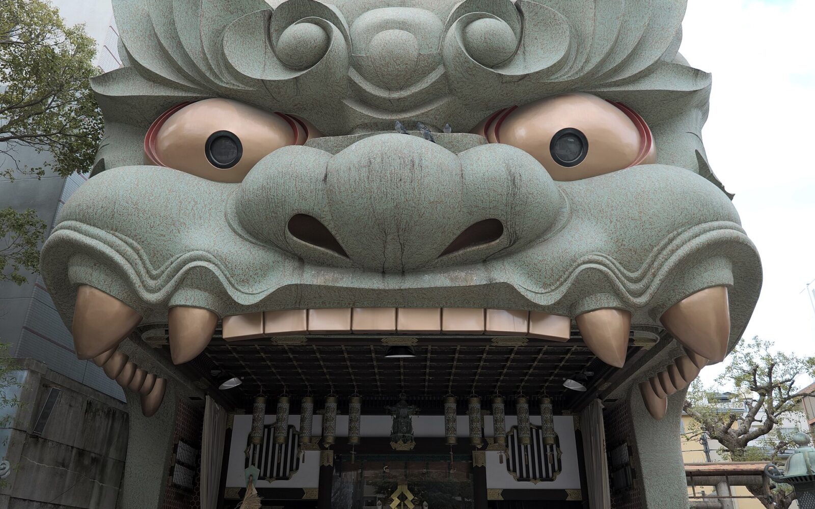 The giant green lion-head stage at Namba Yasaka Shrine in Osaka, with golden eyes and an open mouth.