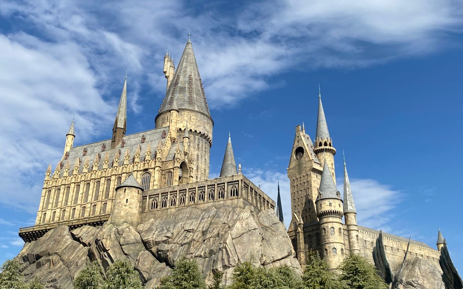 Hogwarts Castle at Universal Studios Japan, its spires and towers rising from a rocky crag against a blue sky with white clouds