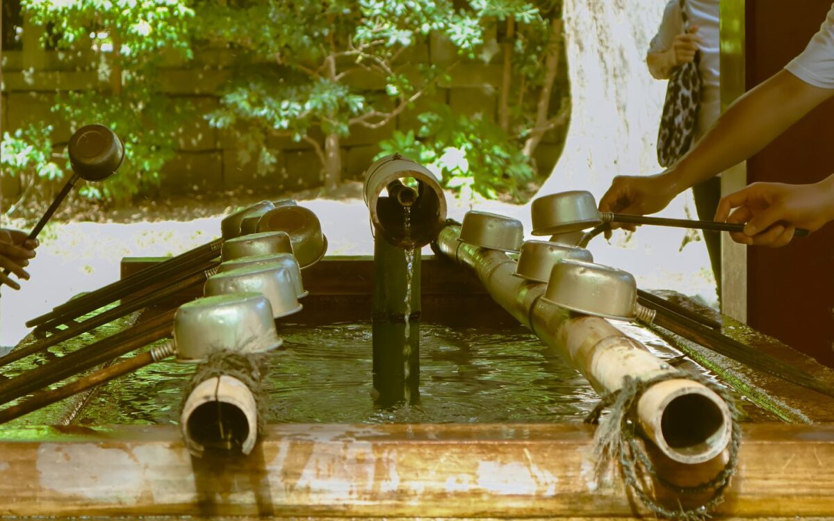 Visitors using bamboo-handled ladles to rinse their hands at a shrine water basin in Japan