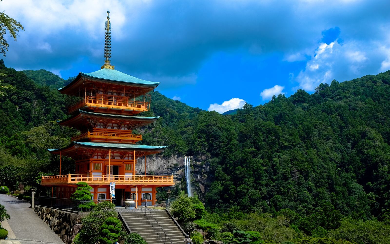The red three-storey pagoda of Seiganto-ji with Nachi Falls dropping down the forested mountainside behind it