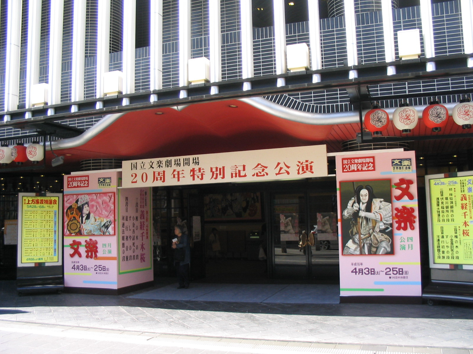 National Bunraku Theatre entrance in Osaka, with a red canopy, paper lanterns and pink programme boards in 2004.