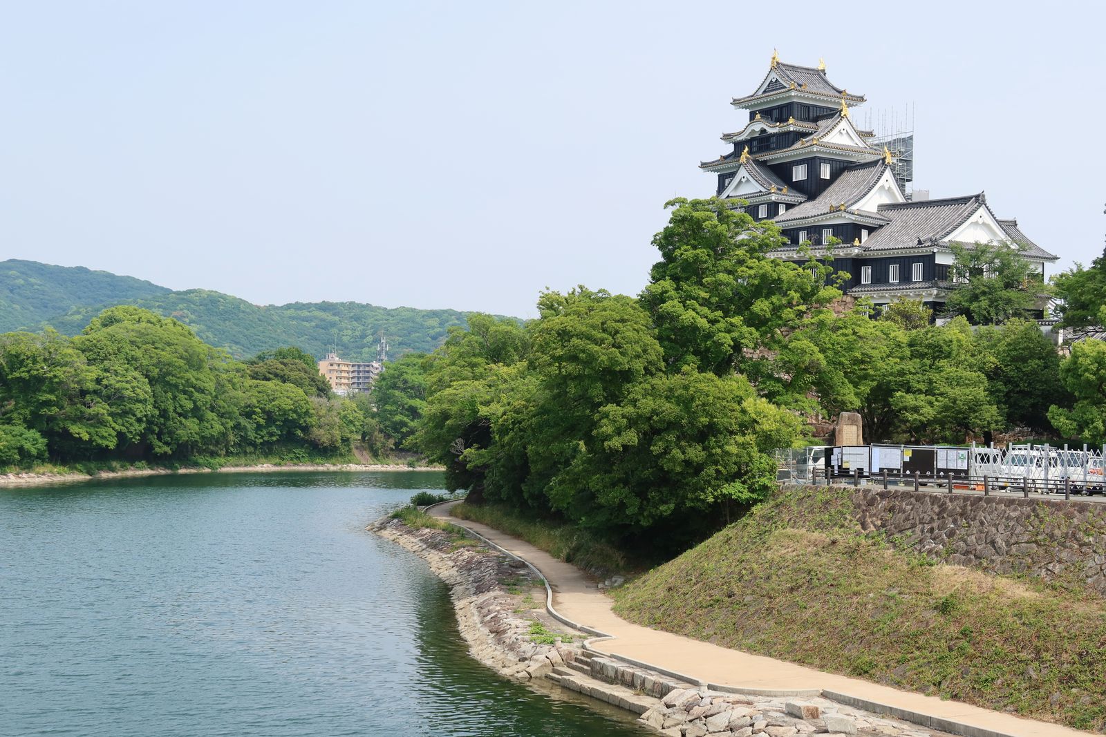 The black multi-storey keep of Okayama Castle above the green banks of the Asahi River