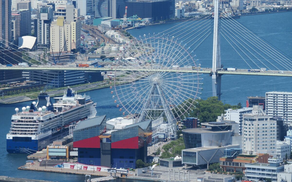 Osaka Aquarium Kaiyukan and the Tempozan Giant Ferris Wheel stand beside the waterfront, with a cruise ship moored nearby.