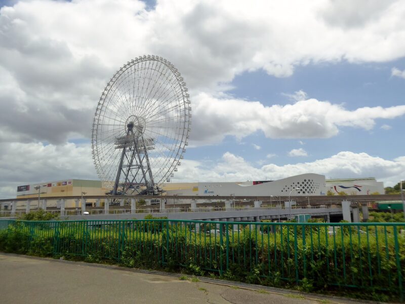 The Osaka Wheel rises above the EXPOCITY shopping complex in Suita beneath a partly cloudy sky.
