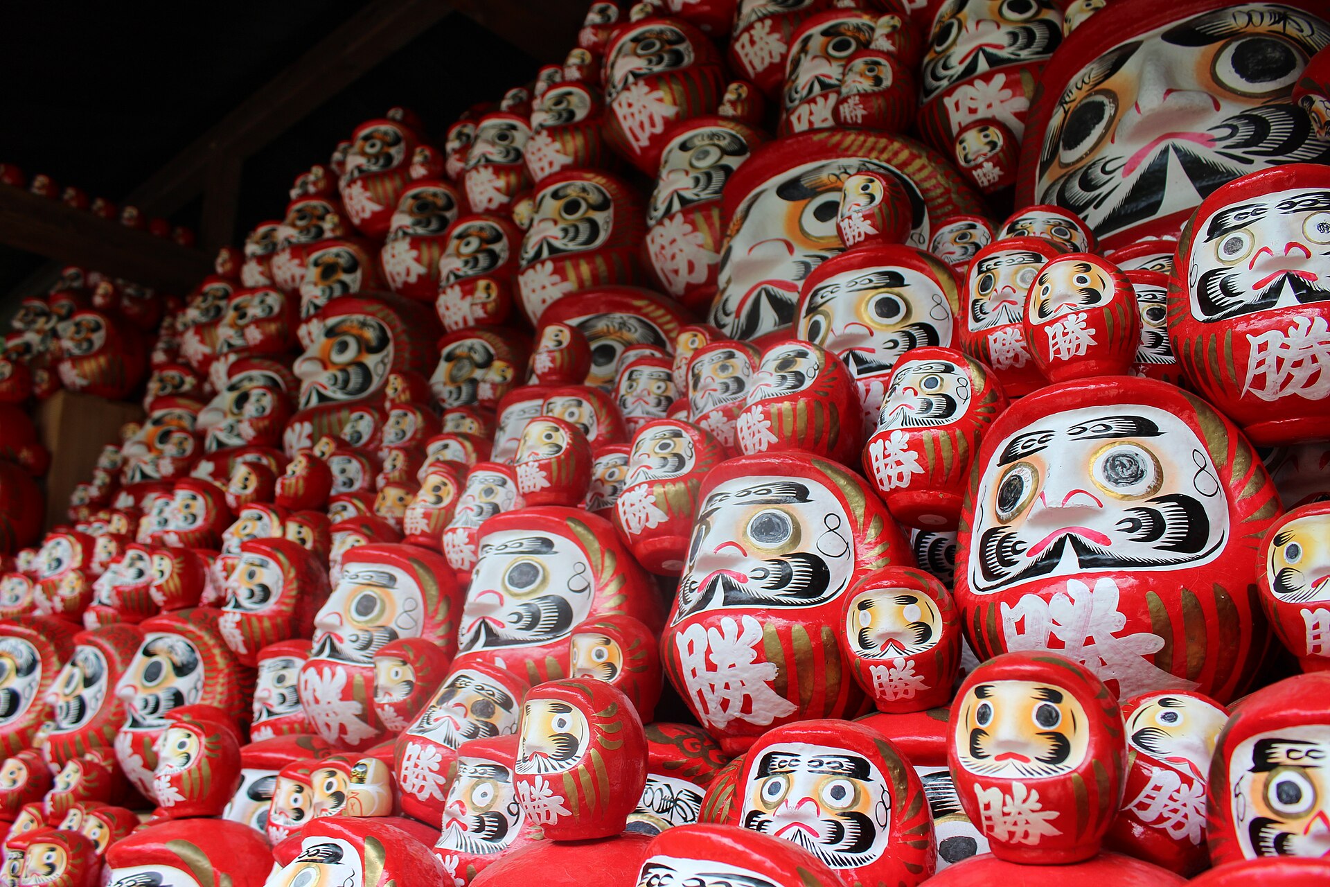 Rows of red daruma dolls with painted faces fill a wooden display at Katsuo-ji temple in Minoh, Osaka Prefecture.