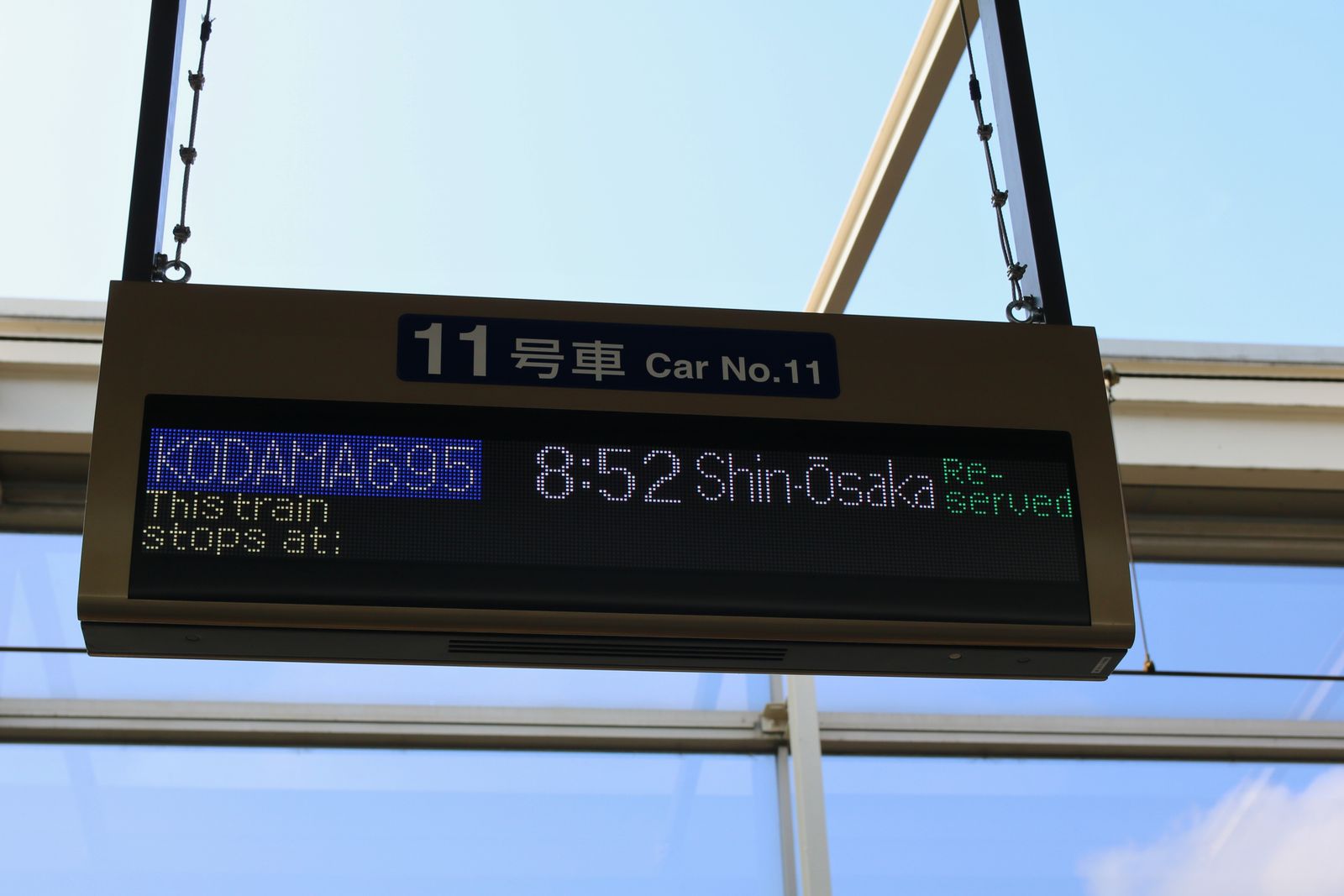 A platform sign for car number 11 showing the Kodama 695 to Shin-Osaka at 8:52 with reserved seats