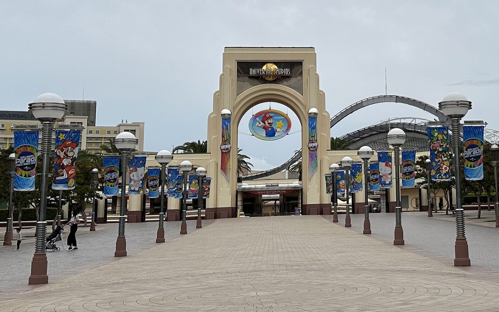 Universal Studios Japan entrance arch rises above a broad plaza lined with colorful banners in Osaka.