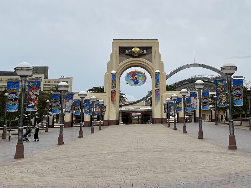 Universal Studios Japan entrance arch rises above a broad plaza lined with colorful banners in Osaka.