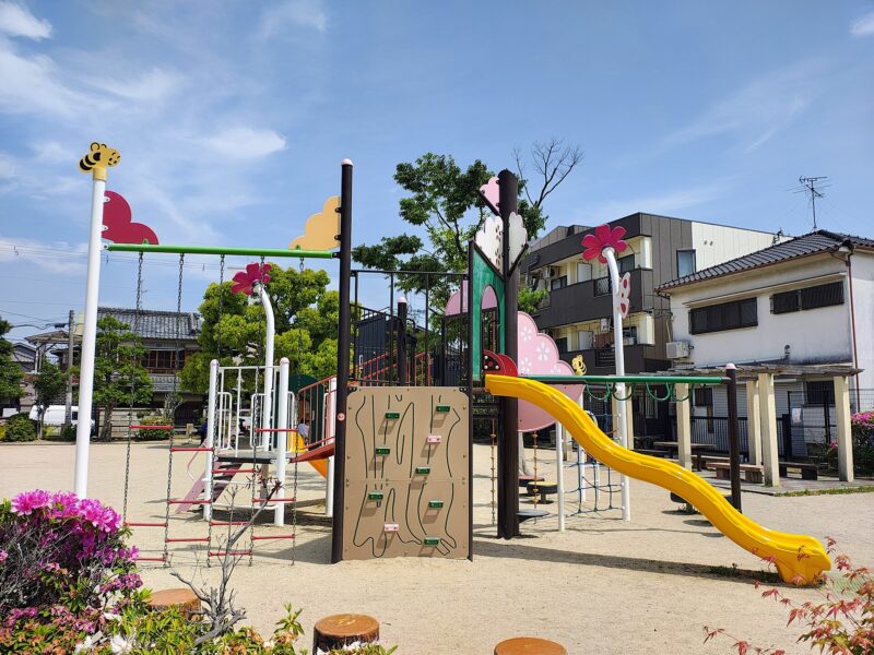 A yellow slide and colorful climbing structure stand in a neighborhood playground in Takatsuki, Osaka Prefecture.